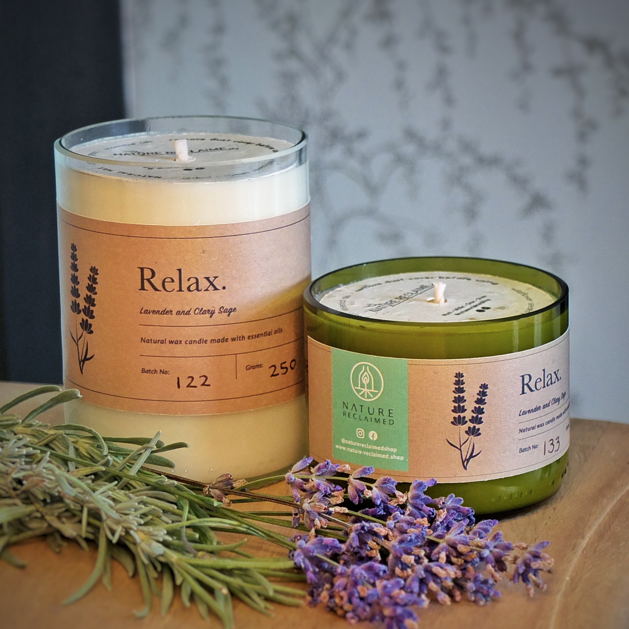 Image of two candles made from upcycled bottles with a sprig of lavender laid in front